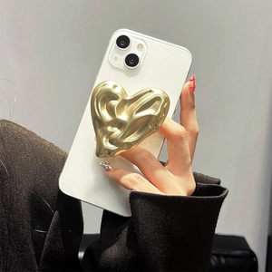 Détail d'un support cœur doré métallique à texture liquide sur un téléphone blanc