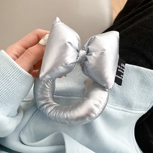 Detail of silver metallic puffy bow charm with woven label on solid leather phone strap