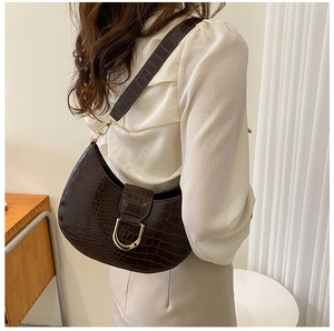 Side view of a brown crocodile pattern half-moon shoulder bag with a gold D-buckle detail