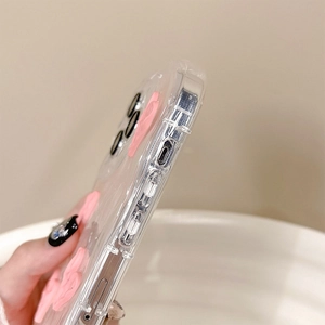 Gros plan d'une coque iPhone transparente avec nœud rose 3D et découpes latérales précises