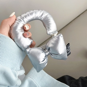 Detail of a puffy silver metallic bow accessory with high-shine finish and stitched label