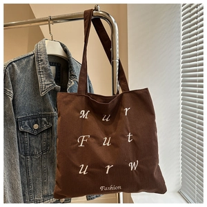 Detailed texture of brown corduroy tote bag with white letter embroidery and fashion logo