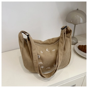 Detail view of khaki corduroy tote bag with white Luck embroidery on a white desk
