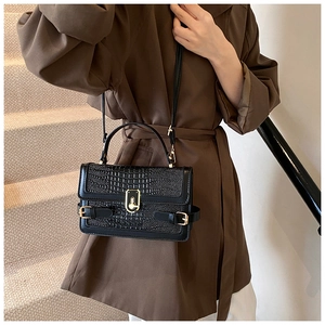 Detail of black crocodile texture PU leather crossbody bag with gold hardware and clasp