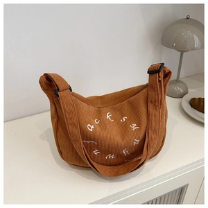 Detailed view of yellow corduroy tote bag with embroidered logo and adjustable strap