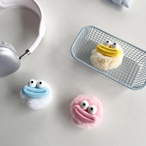 Detail showing plush funny big mouth monster phone grip in pink, white, and beige colors