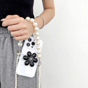 Glossy white phone case with black flower motif and long pearl crossbody chain strap