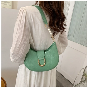 Detail of green faux crocodile leather handbag with pearl strap and gold hardware