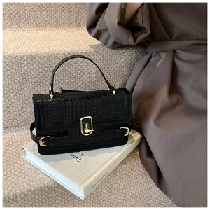 Close-up of black crocodile pattern faux leather handbag with gold metal clasp detail