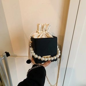Black and white bucket bag with floral embossing, pearl handle, and gold chain strap