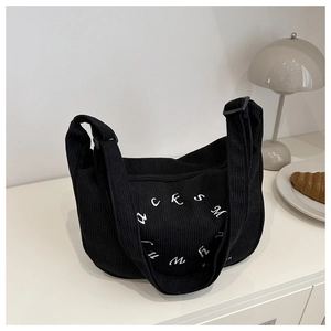 Detail of black corduroy tote bag with white embroidery and adjustable wide strap