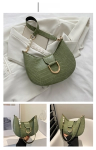 Detail of green faux crocodile leather saddle bag with gold buckle and pearl strap