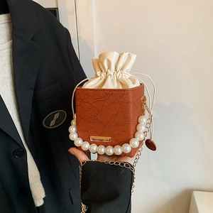 Brown lace-embossed bucket bag with pearl handle and golden chain strap