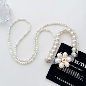 Close-up of pearl crossbody chain with elegant cream flower charm and gold accents