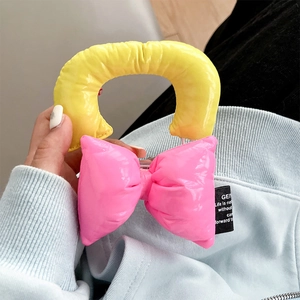 Close-up of a quilted yellow handle and bright pink bow on a glossy leather phone case