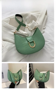 Detail of emerald green crescent bag with crocodile pattern and pearl strap detail