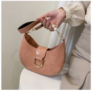 Detail of pink faux crocodile leather bag with pearl handle and golden U-shaped buckle