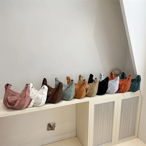 Minimalist corduroy crossbody bags in various colors on a white minimalist shelf display