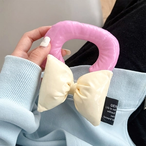 Close-up of a puffy pink and beige faux leather bow strap with glossy finish