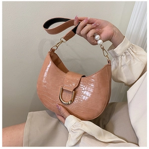 Detail of coral faux crocodile leather bag featuring pearl handle and gold buckle