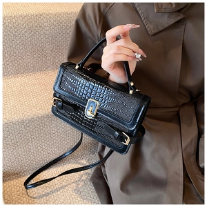 Detailed view of crocodile pattern PU leather texture with gold metal clasp on handbag