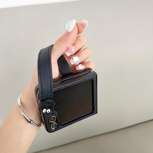 Dettaglio custodia Z Flip 5 in pelle nera con cinturino e decoro spiritello fuliggine