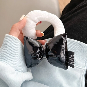 Detail of a chic black and white leather bow wristband charm with a brand logo label