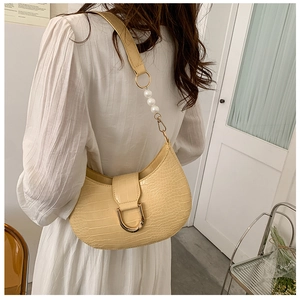 Detail of beige crocodile pattern half-moon bag with gold D-buckle and pearl strap