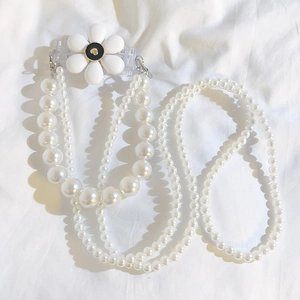 Detailed view of dual-layer pearl strap with white flower charm and metal hooks