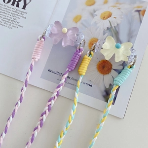 Detail of woven crossbody phone straps with acrylic bows in pastel pink and blue colors
