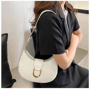 Detail of white crocodile embossed half-moon hobo bag with a gold metal buckle