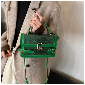 Close-up of green crocodile embossed faux leather handbag with vintage gold square lock