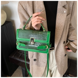 Detail of green faux crocodile leather handbag with elegant gold twist lock closure