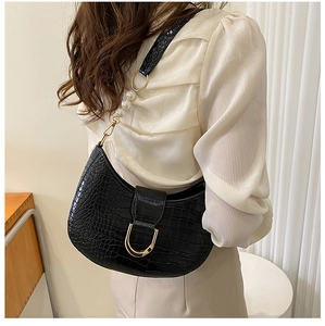 Detail of black faux crocodile leather crescent bag with white pearl chain and gold hardware
