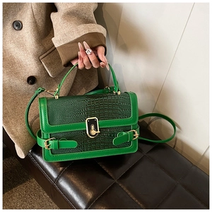 Detail of green crocodile texture flap bag with elegant gold metal clasp and top handle