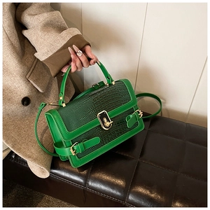 Detail of bright green crocodile texture PU leather handbag with gold metal clasp and strap
