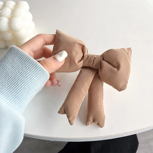 Detail of latte brown 3D bow phone strap with vertical fabric texture and long ribbons