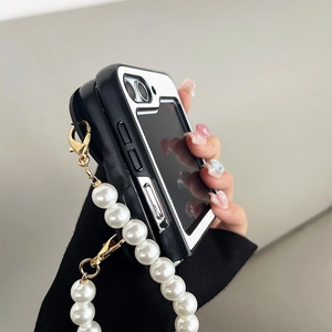 Detail view of folding phone case with pearl chain strap and black-white contrast design