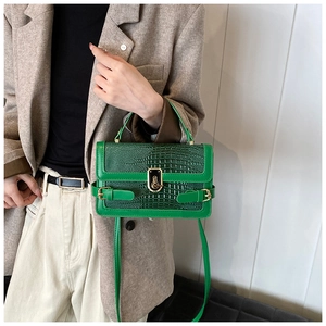 Detail of green crocodile embossed bag featuring a vintage gold twist lock and fine texture