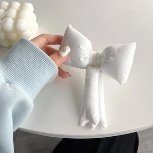 Detailed close-up of a large 3D white padded fabric bow accessory with soft texture