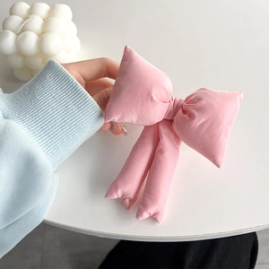 Detail of pink padded fabric bow phone clip showing three-dimensional texture and soft color