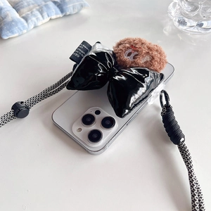 Detail of plush bear and black bow on iPhone case with crossbody braided strap