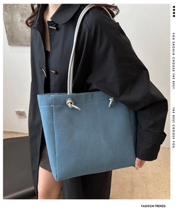 Detail of blue denim tote bag with thick grey rope shoulder strap and knot accents