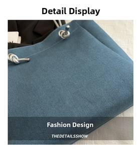 Detail of blue denim tote bag showing fine fabric texture and thick rope shoulder strap