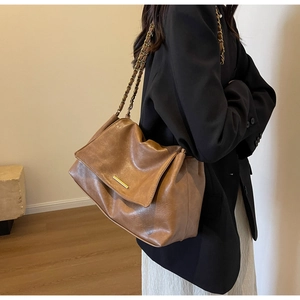 Detailed close-up of brown vintage shoulder bag with gold metal buckle and chain strap