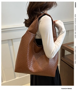 Detail showing the intricate intrecciato weave pattern on a caramel leather tote bag