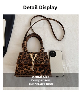 Dettaglio borsa leopardata con logo V dorato e nappa metallica accanto a un telefono