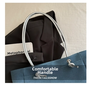 Detail of blue denim tote bag featuring thick silver metallic rope handle and metal rings