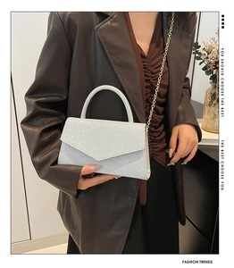Close-up of sparkling silver glitter square bag with gold chain and top handle