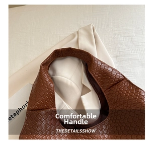 Detail view of brown woven leather texture and soft shoulder strap on a chic tote bag